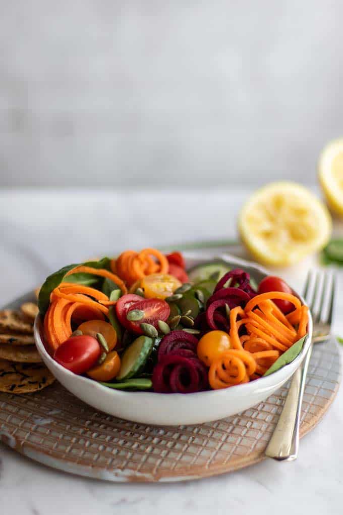A green salad topped with carrots, beets, tomatoes, and pumpkin seeds.