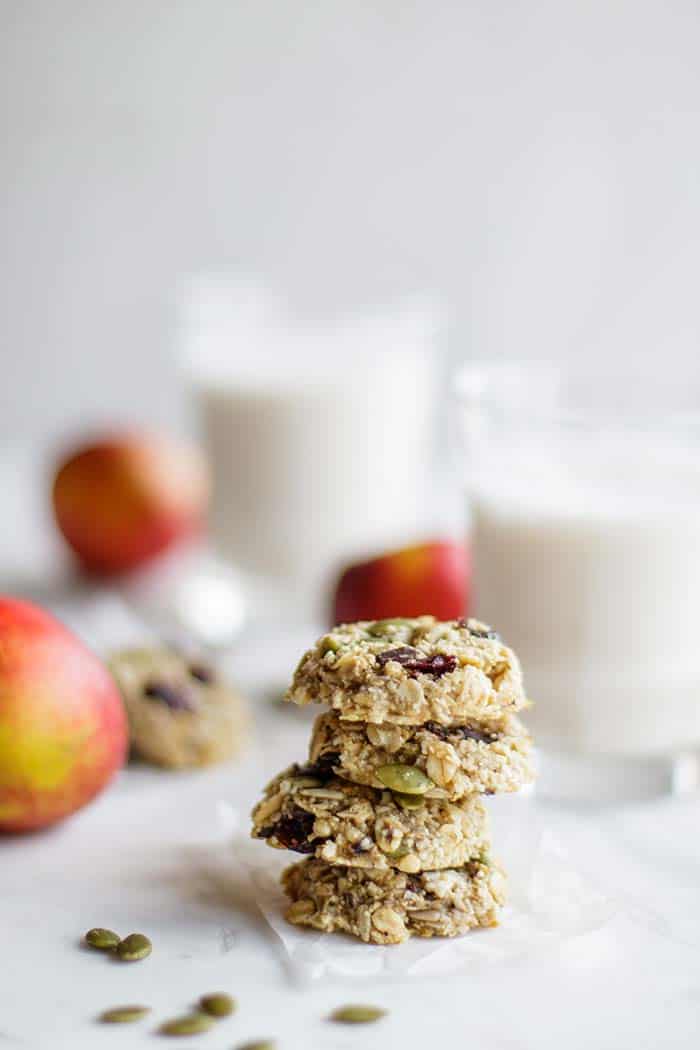 A stack of 4 banana breakfast cookies in front of a glass of milk.