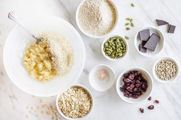 A bowl of mashed banana, surrounded by all the ingredients for banana breakfast cookies.