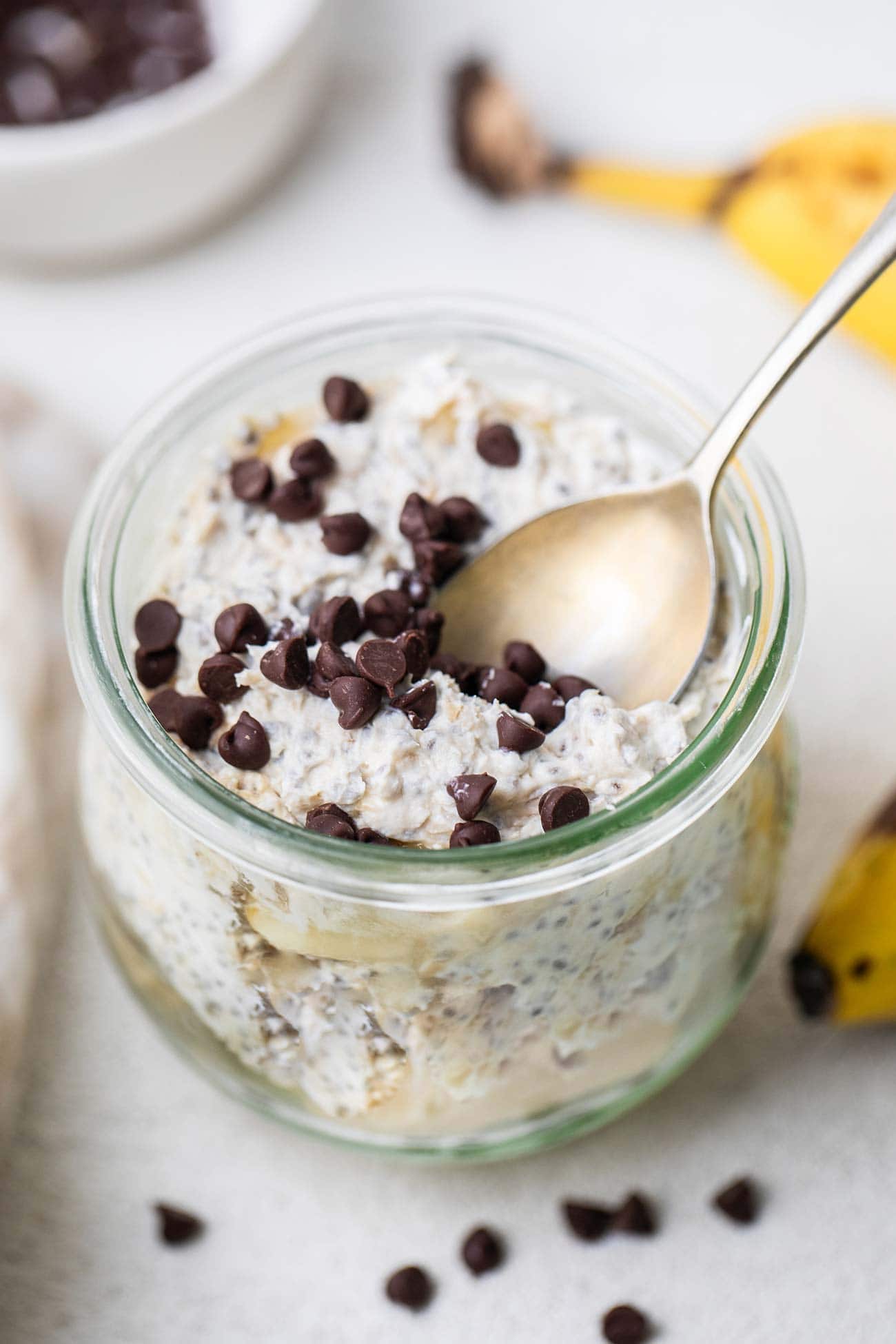 A jar filled with cookie dough overnight oats with a gold spoon.