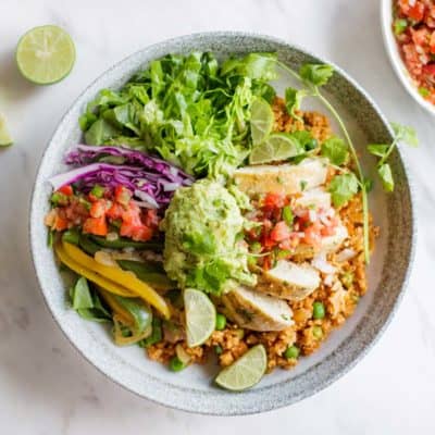 A whole30 chipotle bowl recipe showing chicken, cauliflower rice, lettuce and salsa.