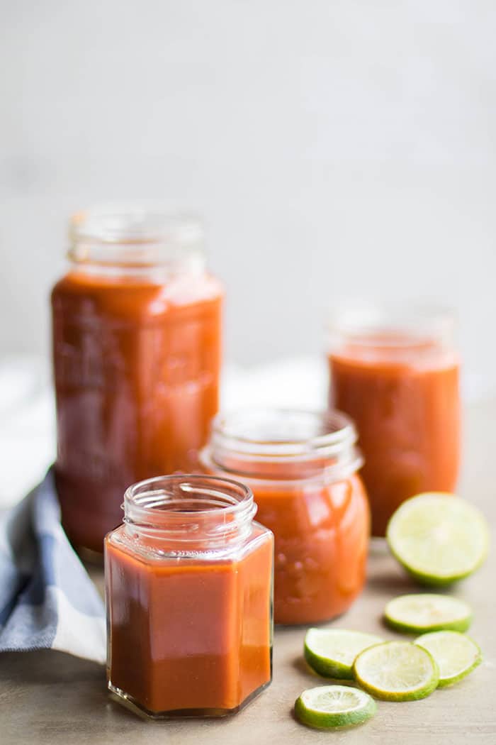 Jars of homemade enchilada sauce with slices of lime.