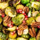 A close up look at roasted brussels sprouts tossed with pecans and pomegranate.