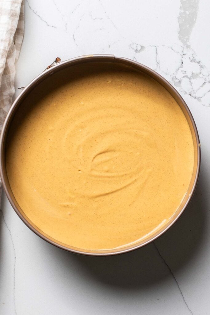 A creamy pumpkin mixture smoothed over a graham cracker crust in a springform pan.