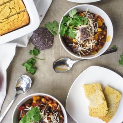 A bowl of chicken taco chili with chips and cilantro on it.