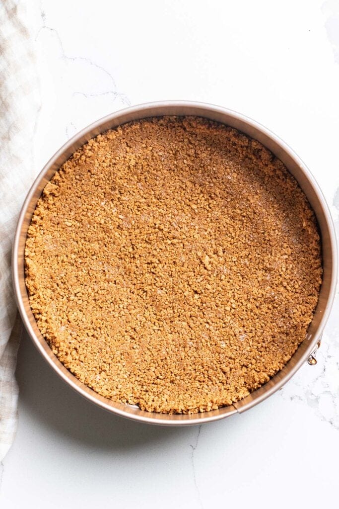 Graham cracker crumbs pressed into a springform pan to form a crust.