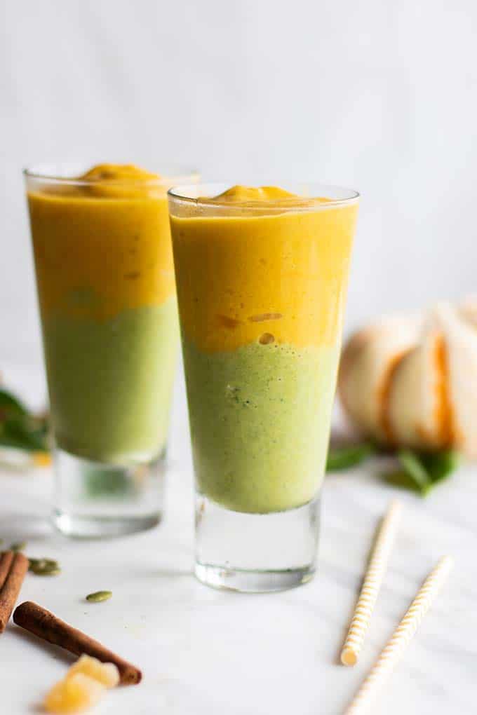 Two pumpkin smoothies with a green layer and a pumpkin layer.
