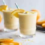 A healthy whole fruit orange smoothie in a clear glass.