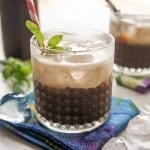 A glass filled with coffee concentrate, floated with creamy coconut milk.