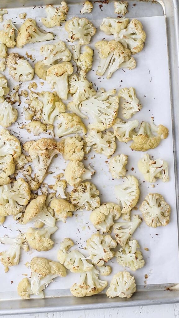 Roasted cauliflower on a baking tray showing browned edges,