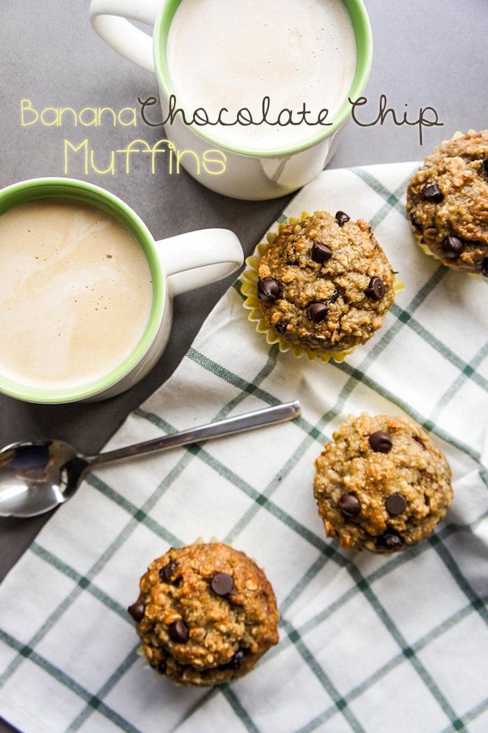 4 muffins on a towel next to two mugs of coffee.