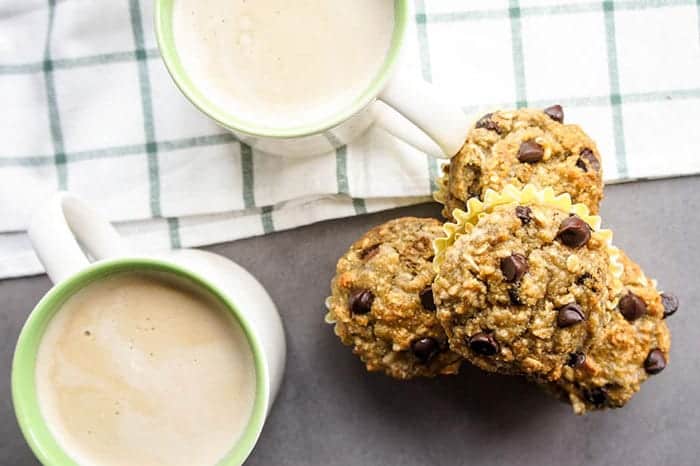 4 gluten free banana muffins stacked next to a latte.