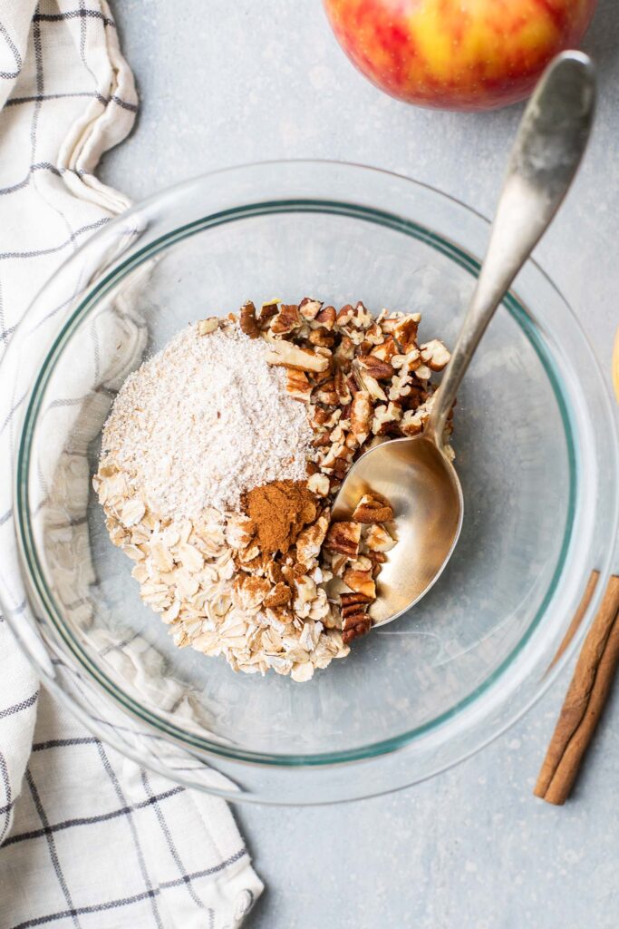 Oats, pecans, and cinnamon combined in a bowl.