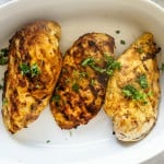 3 Pieces of grilled moroccan chicken in a serving dish.