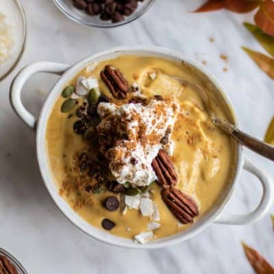 A festive fall smoothie bowl topped with whipped cream and pecans.