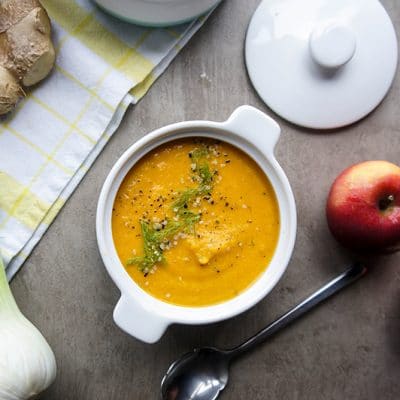 A bowl of carrot apple fennel soup with additional ingredients.