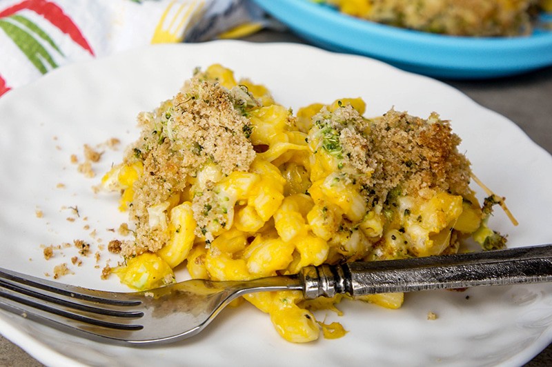 A plate of macaroni and cheese with a broccoli and bread crumb topping.