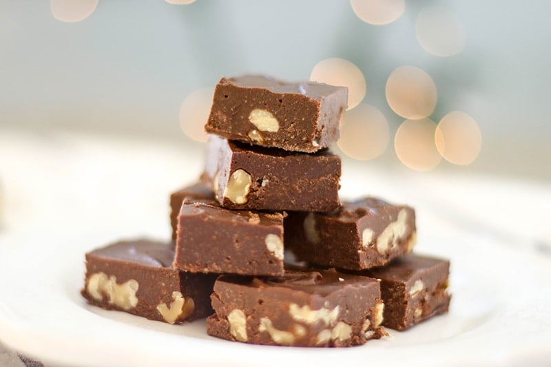 A stack of paleo fudge with walnuts on a white plate.