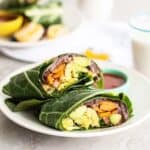 A collard wrap breakfast burrito on a plate with salsa to dip.