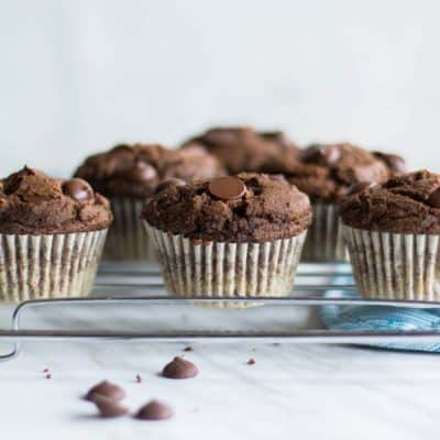 Lots of gluten free double chocolate chip muffins sitting on a cooling rack.