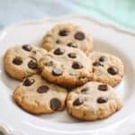 A close up of a stack of paleo chocolate chip cookies on a white plate.