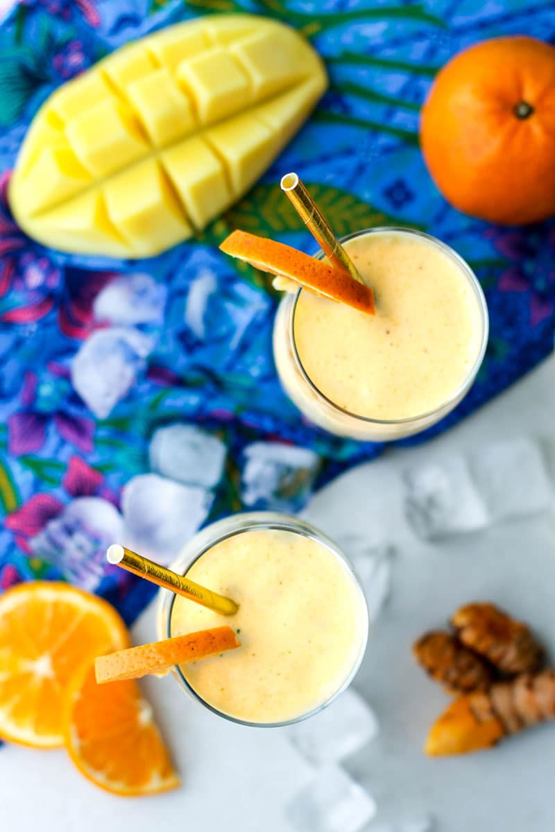 A top view of two smoothies in glasses over a blue linen napkin.