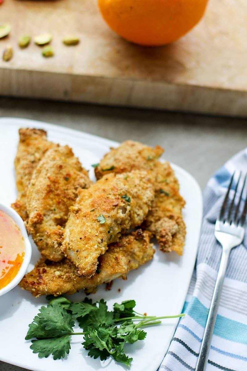 A close up view of a plate of baked chicken fingers.