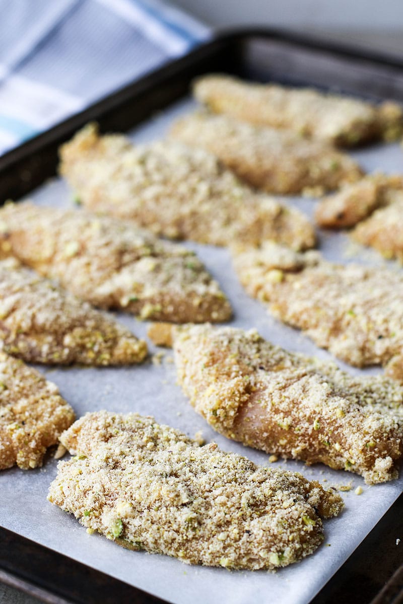 Pieces of chicken coated in egg and a pistachio flour.