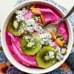 A pitaya bowl topped with colorful fruit, almonds and coconut.