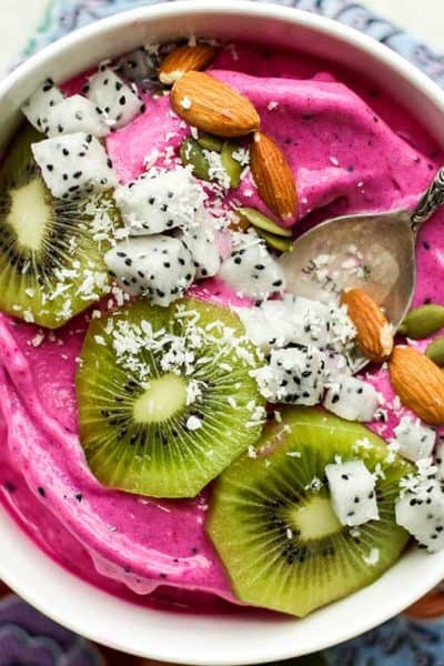 A pitaya bowl topped with colorful fruit, almonds and coconut.