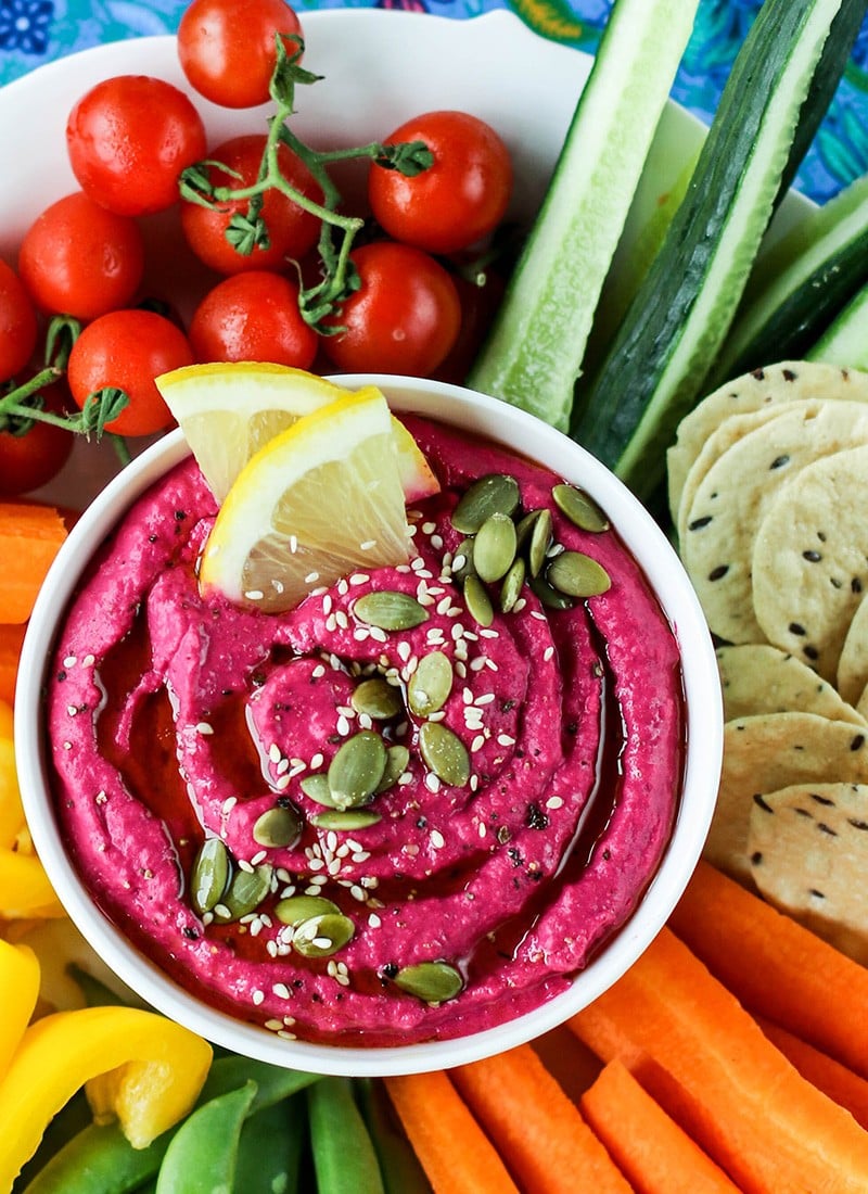 A close up shot of beet hummus topped with pumpkin and hemp seeds.