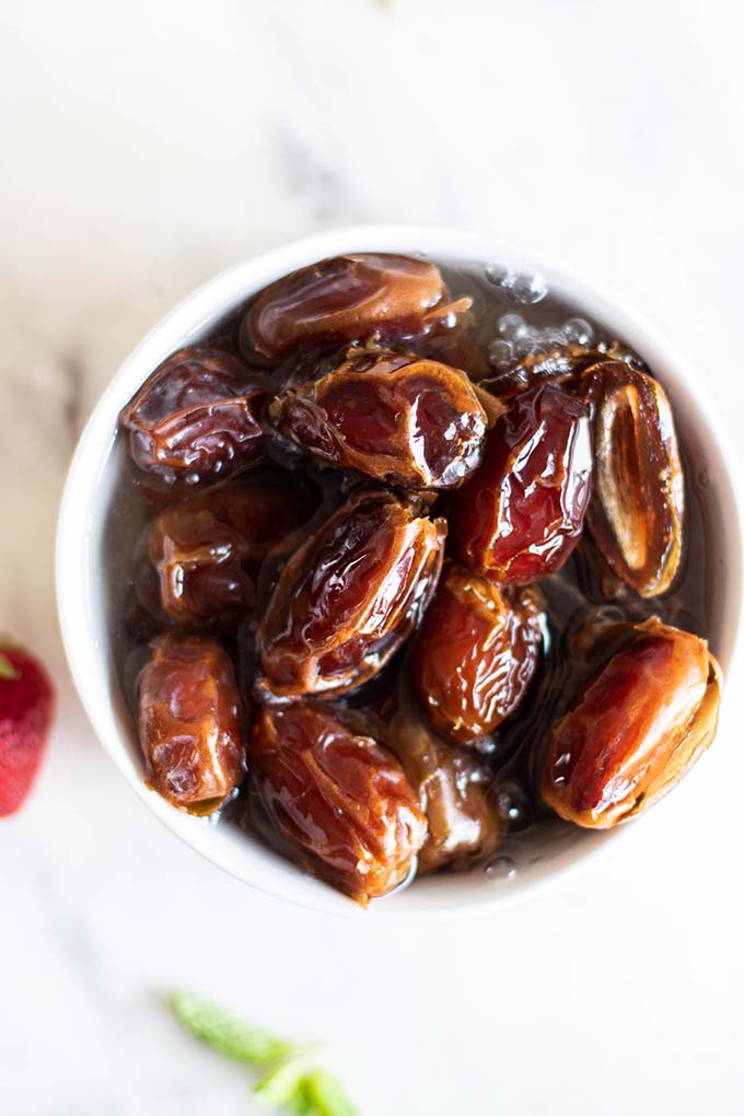 A bowl of medjool dates soaking in hot water.