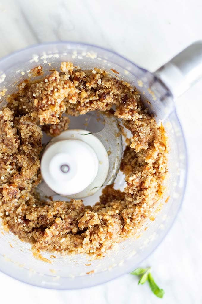 Quinoa and dates processed in a food processor bowl.