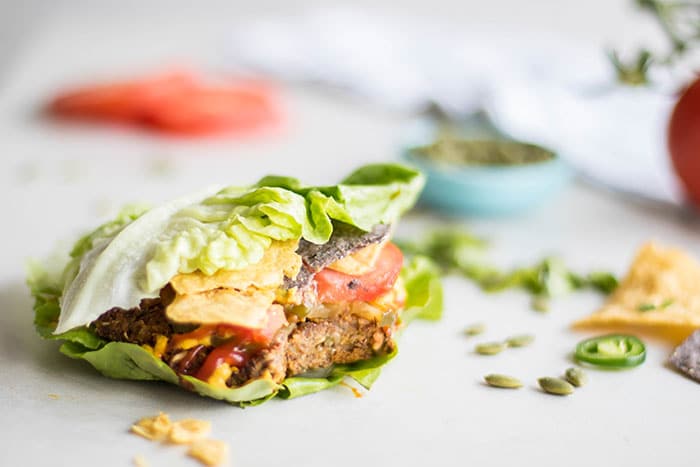 A veggie burger shown wrapped in lettuce with optional toppings.