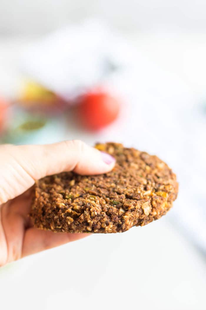 A pumpkin seed veggie burger shown held in hand to show its firmness.