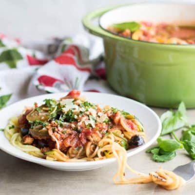 A plate with zoodles topped with chicken sausage spaghetti sauce.