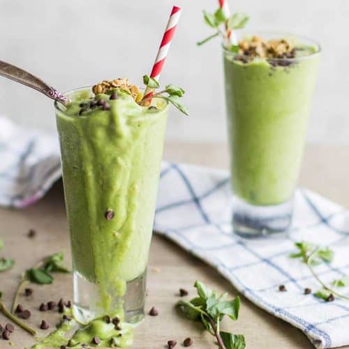 Two Chocolate Chip Mint Smoothies spilling out of the glasses.