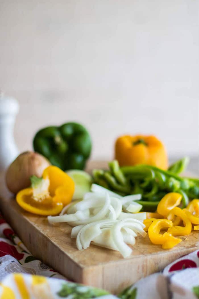 A cutting board with chopped onions and peppers, ready to add to the spaghetti sauce.