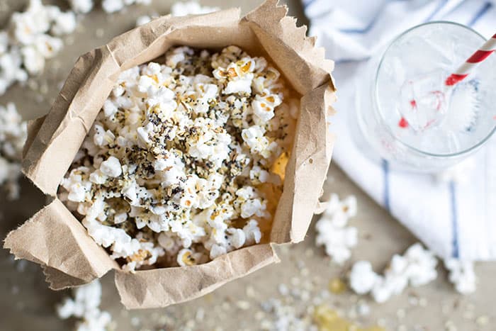 A paper bag willed with popcorn and sprinkled with everything bagel seasoning.