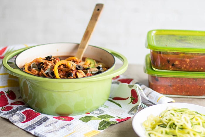 A pot of chicken vegetable spaghetti sauce, showing enough for 2 meals packed in freezer containers.