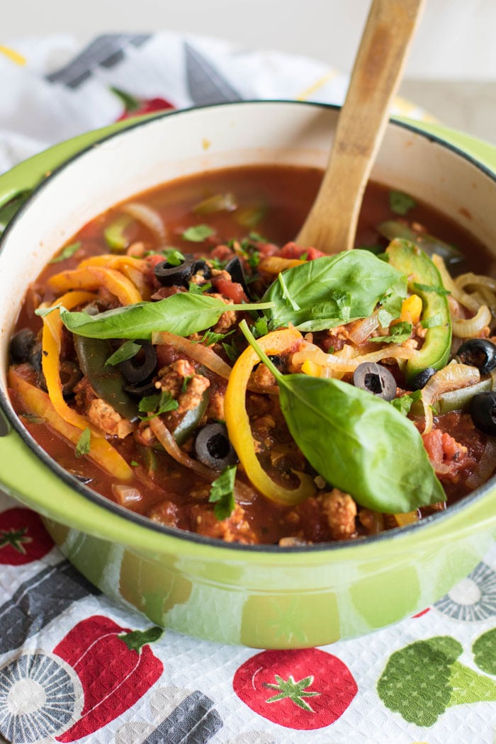 A green pot filled with a chunky homemade chicken spaghetti sauce.