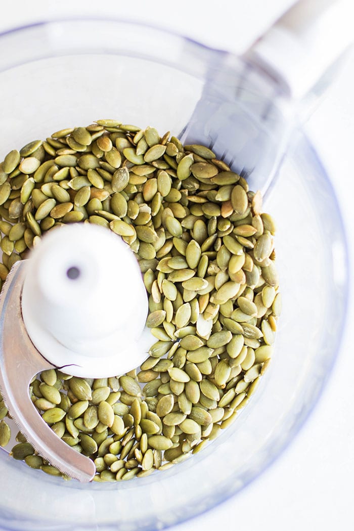 A food processor filled with pumpkin seeds.