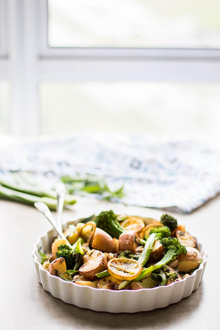 A serving dish filled with roasted vegetables on a table in front of a window.