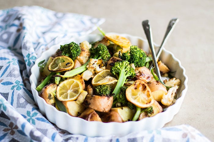 A dish filled with roasted vegetables with leeks and lemons.