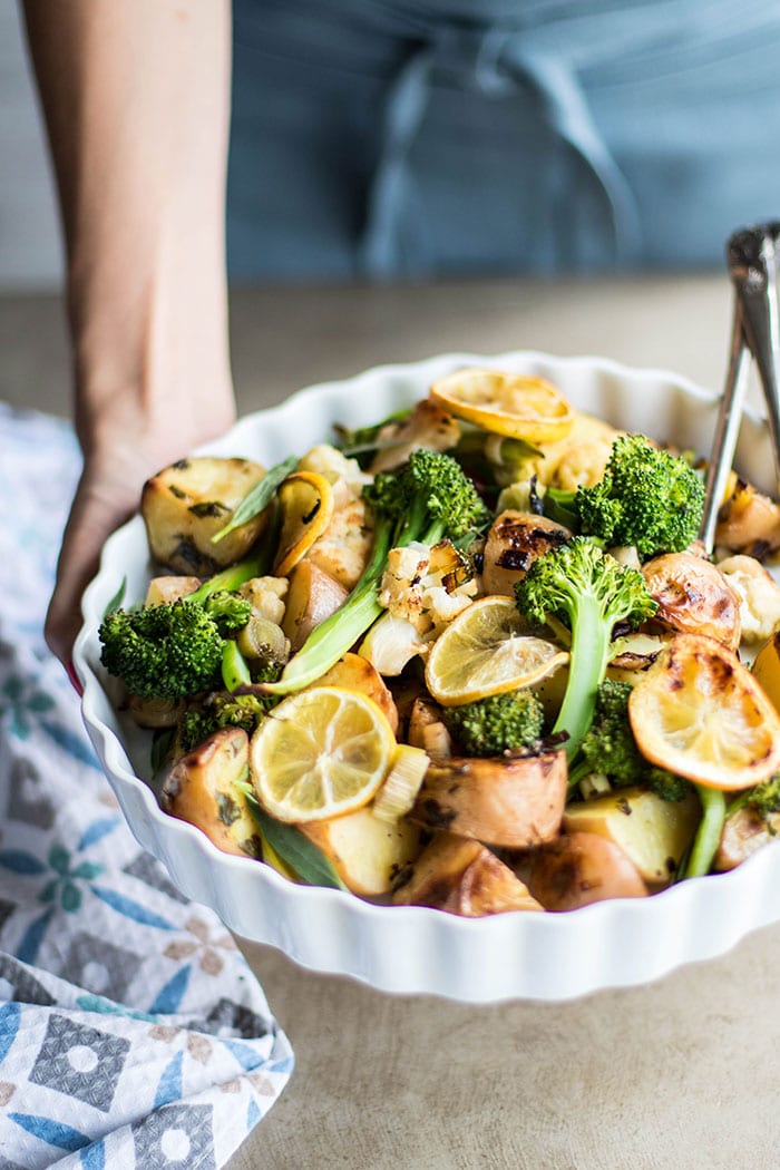 Michelle holding a serving dish filled with spring roasted vegetables.