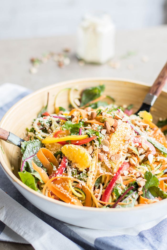 A white bowl sitting on a towel filled with Asian Orange Zoodle Salad.