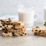 A stack of oatmeal raisin protein bars and a glass of almond milk.