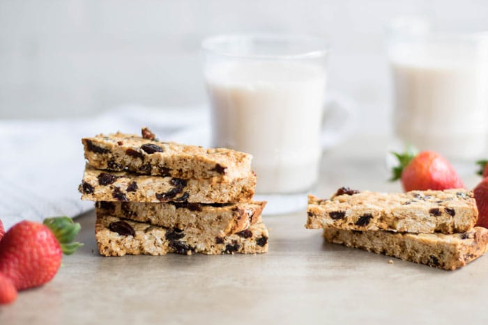 A stack of oatmeal raisin protein bars and a glass of almond milk.