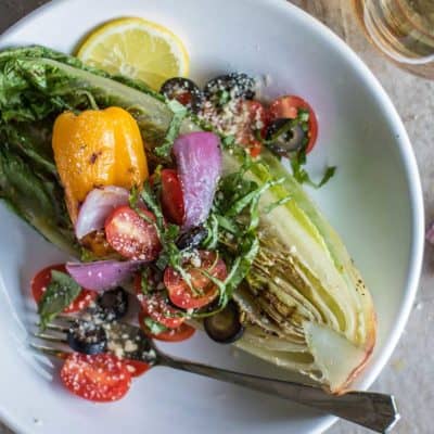 Grilled Romaine Salad topped with grilled peppers, onions, tomatoes and basil.