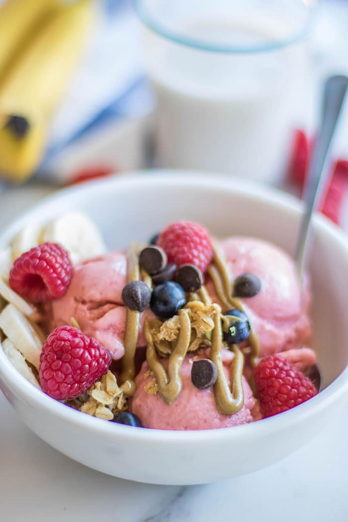 A close up view of a healthy breakfast sundae topped with berries, bananas, and granola.